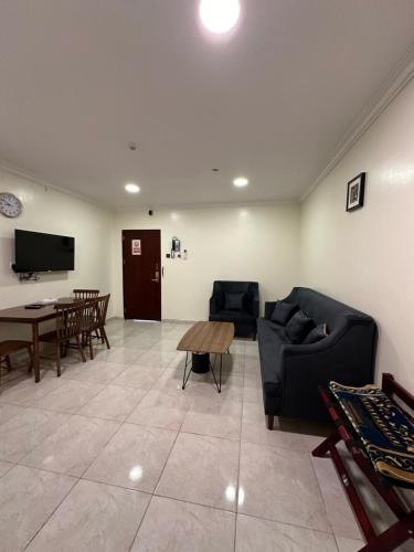 sala de estar con sillas, mesa y TV en Danat Layalina Apparthotel, en Al Namas