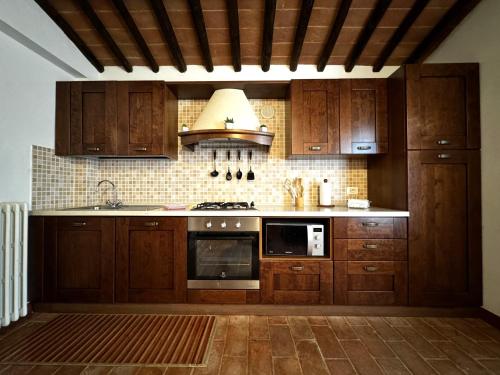 a kitchen with wooden cabinets and a stove top oven at Agriturismo LeGi Toscana in Pietraviva