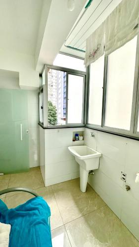 a bathroom with a sink and two windows at Apê Curitiba I Familiar, tranquilo e sossegado in Belo Horizonte