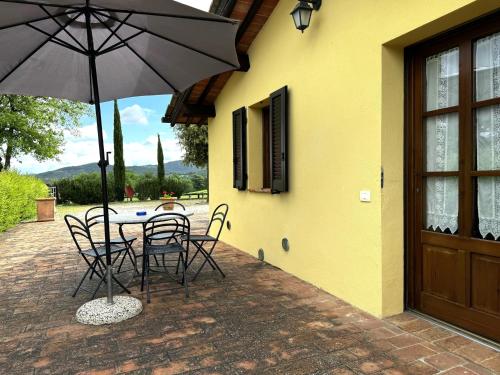 a patio with a table and chairs and an umbrella at Agriturismo LeGi Toscana in Pietraviva