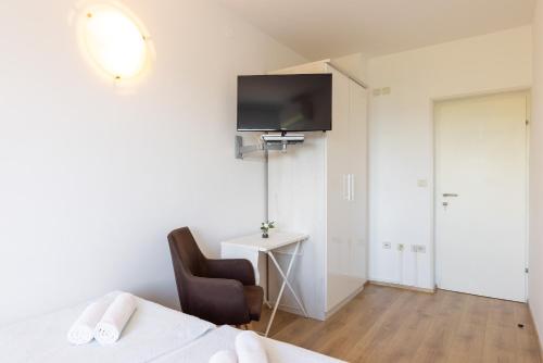 a bedroom with a bed and a chair and a tv at Seaside Guesthouse by JR City Apartments in Jadranovo