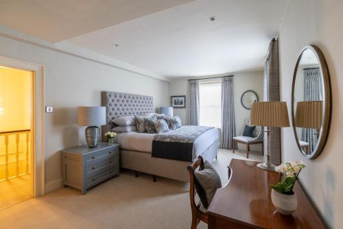 a bedroom with a bed and a desk and a mirror at St Martin's House in Chichester