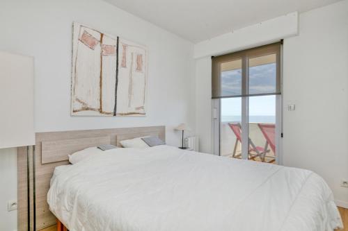 une chambre blanche avec un grand lit et une fenêtre dans l'établissement Appartement face mer sur plage, à La Baule