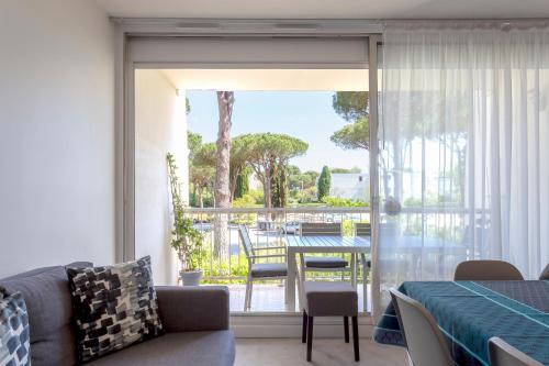 un salon avec un canapé et une porte coulissante en verre dans l'établissement Chez Marylène - Spacieux appartement proche des plages & commerces, à La Grande Motte