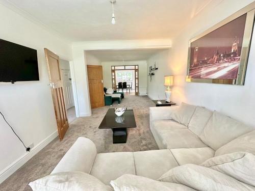 a living room with a white couch and a tv at Long Term Comfort - Modern 3BR Retreat with Free Parking & WiFi in Enfield Lock