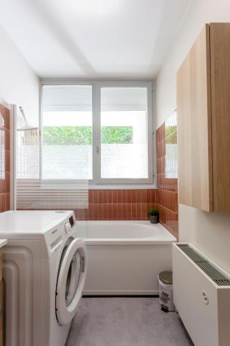 une salle de bain avec baignoire et machine à laver dans l'établissement Chez Marylène - Spacieux appartement proche des plages & commerces, à La Grande Motte