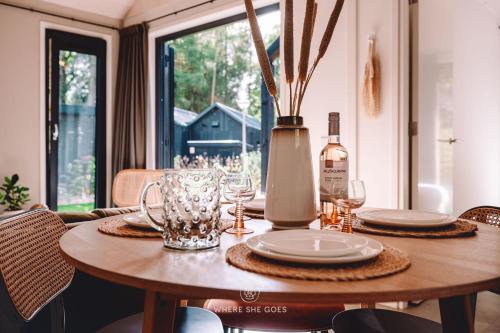 stół z talerzami i kieliszkami oraz butelkę wina w obiekcie GrØn Tiny House w mieście Epe