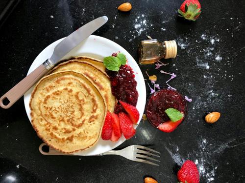a plate of pancakes and strawberries on a table at Hotel Moon Taj Near Yashobhoomi Convention Centre in New Delhi