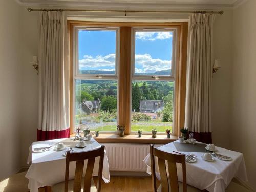un comedor con 2 mesas y una ventana grande en Beinn Bhracaigh, en Pitlochry