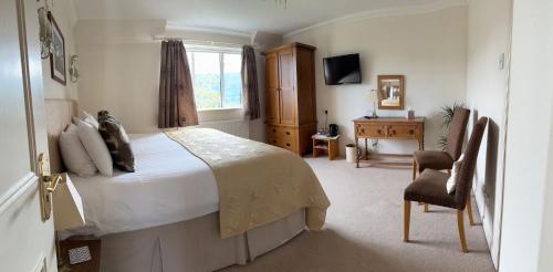1 dormitorio con cama, silla y escritorio en Beinn Bhracaigh, en Pitlochry