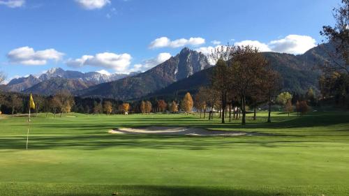 a view of a golf course with mountains in the background at Appartamento - Cave del Predil in Cave del Predil