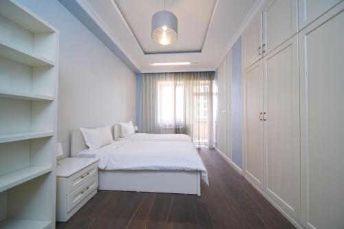 a white bedroom with a bed and a window at Sweet Home Apart-Hotel in Yerevan