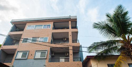 a tall brick building with a palm tree in front of it at The Jam Lodge in Freetown