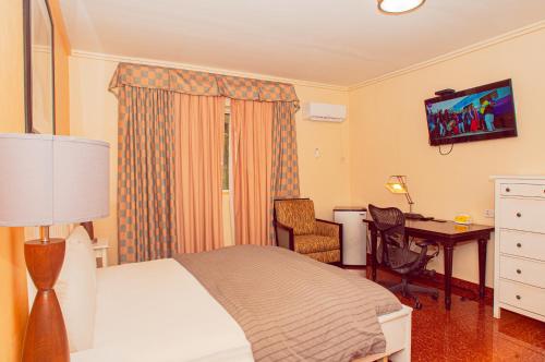 a bedroom with a bed and a desk with a computer at The Jam Lodge in Freetown