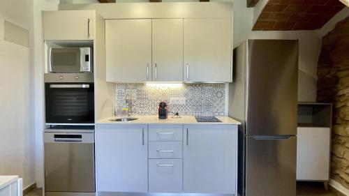 a kitchen with white cabinets and a stainless steel refrigerator at Mas Pigem in Pals