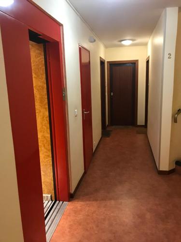 un couloir d'une pièce avec des portes rouges et de la moquette dans l'établissement Studio Paris JO, à Paris