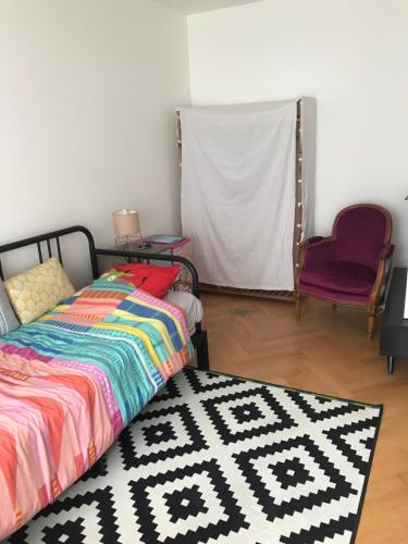 - une chambre avec un lit, un tapis et une chaise dans l'établissement Studio Paris JO, à Paris