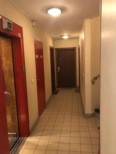 - un couloir avec des portes rouges et du carrelage dans l'établissement Studio Paris JO, à Paris