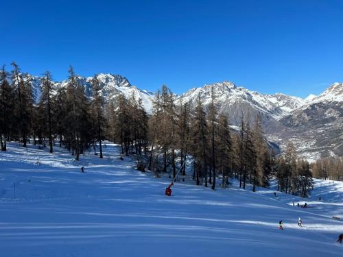 a group of people skiing down a snow covered slope at "La bâtisse des prés" in Puy-Saint-Vincent