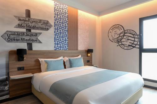 a bedroom with a large bed and signs on the wall at Occidental Tanger in Tangier