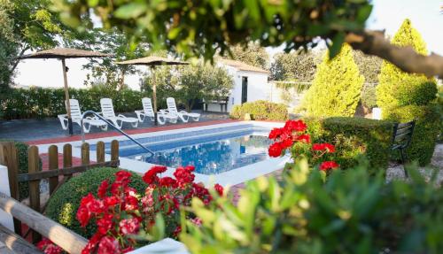 a swimming pool in a yard with red flowers at Casa Rural La Loba in Malcocinado