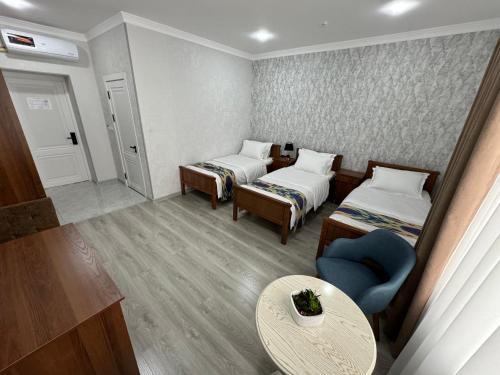 a small room with two beds and a table at DSF GARDEN HOTEL in Yakkasaray