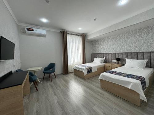 a hotel room with two beds and a flat screen tv at DSF GARDEN HOTEL in Yakkasaray
