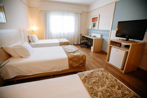ロンドリーナにあるComfort Suites Londrinaのベッド2台と薄型テレビ付きのホテルの部屋