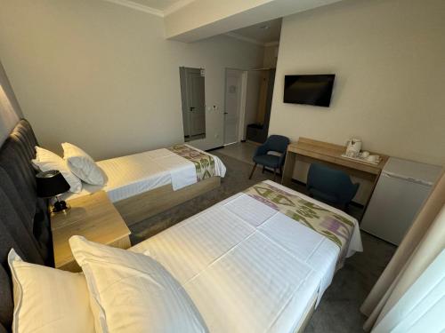 a hotel room with two beds and a desk at DSF GARDEN HOTEL in Yakkasaray