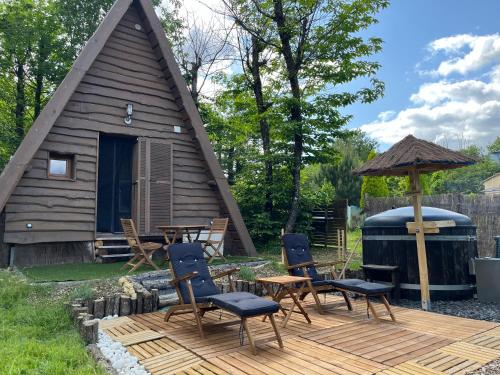 a cabin with a wooden deck with chairs and an umbrella at La cabane des amoureux in Sarlat-la-Canéda