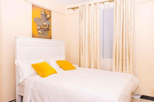 ナニュキにあるUrbanS 1 Bedroom bnb Nanyukiのベッドルーム1室(白いベッド1台、黄色い枕2つ付)