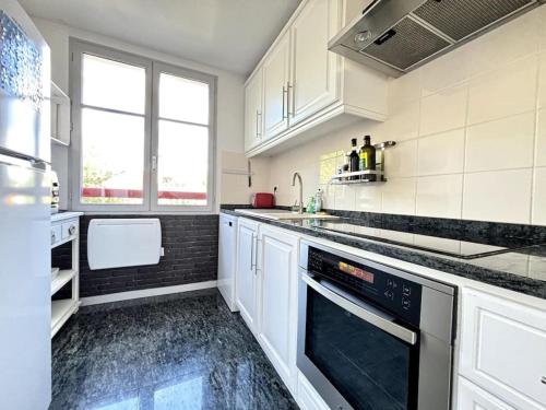 La cuisine est équipée de placards blancs et d'un lave-vaisselle. dans l'établissement Agréable appartement proche de la mer, à Arcachon