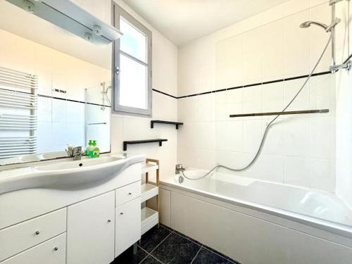 une salle de bain blanche avec un lavabo et une baignoire dans l'établissement Agréable appartement proche de la mer, à Arcachon