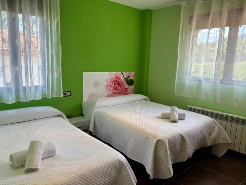 two beds in a room with green walls and windows at La Libélula in El Espinar