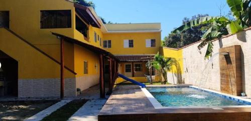 a house with a swimming pool in front of a building at Casa Vale da Paz - Massaguaçu. in Caraguatatuba