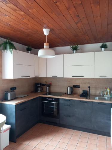 una cucina con armadi bianchi e soffitto in legno di Penzion U Sochoru a Pec pod Sněžkou
