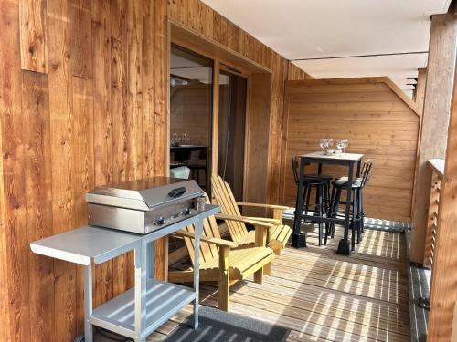 une terrasse avec une cuisinière, une table et des chaises dans l'établissement Bel appartement neuf aux Gets, proche des pistes, avec terrasse et parking sécurisé - FR-1-623-335, aux Gets