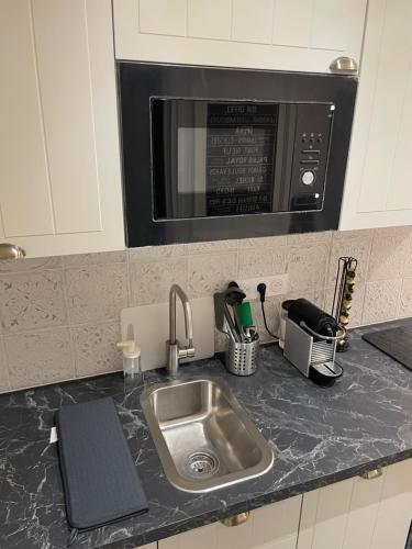 un comptoir de cuisine avec un évier et un micro-ondes dans l'établissement Montmartre Cosy, à Paris