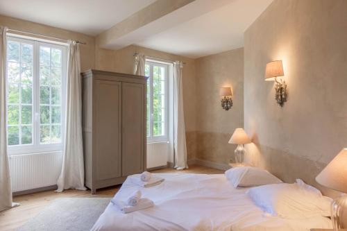 a bedroom with a large white bed and two windows at Maison chaleureuse de 4 à 12 personnes in Neuville-aux-Bois