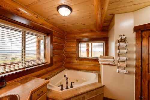 baño con bañera, lavabo y ventana en Luxe Lodge in the Tetons for Large Group Retreats! en Newdale
