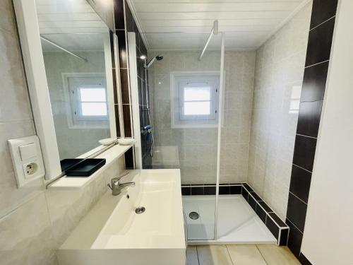 une salle de bain blanche avec un lavabo et une douche dans l'établissement La Sionnaise, à Plage-des-Demoiselles