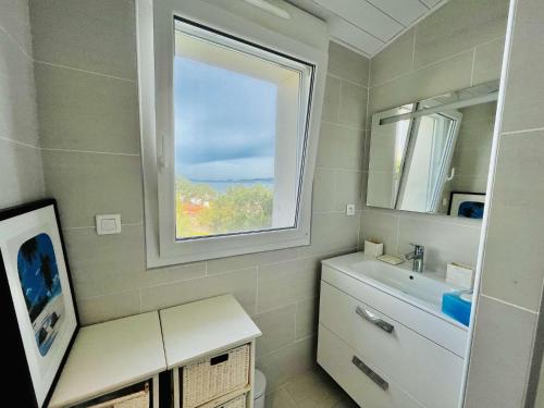 une salle de bain avec un lavabo et une fenêtre dans l'établissement Maison 4 pièces PIETROSELLA, à Pietrosella