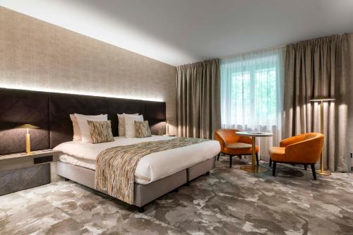 um quarto de hotel com uma cama, uma mesa e cadeiras em Van der Valk Waterloo em Waterloo