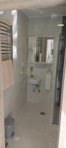 a white bathroom with a sink and a toilet at Relax for you Apartmanház in Cserkeszőlő