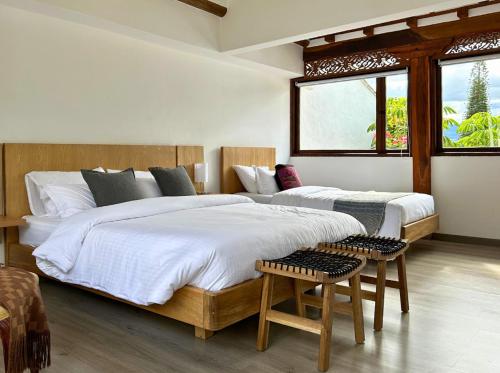 a bedroom with two beds and two windows at Extraordinaria Casa en el Centro Histórico Villa de Leyva - Sol de Iguaque in Villa de Leyva