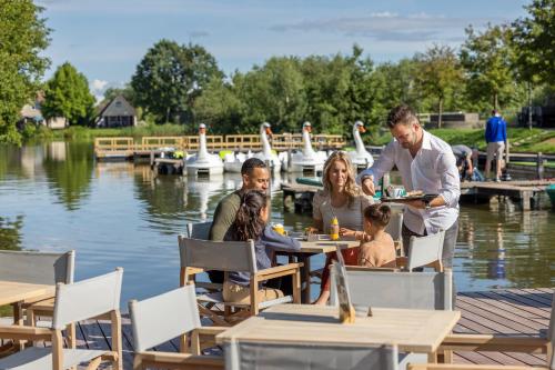 a group of people sitting at a table by the water at Center Parcs Sandur Emmen in Emmen
