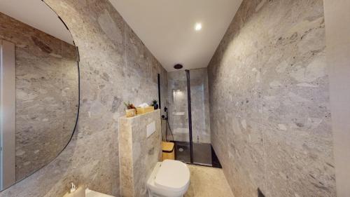 La salle de bains est pourvue de toilettes et d'un mur en pierre. dans l'établissement ApartHotel Riviera - BALCON BARLA - Old Port PLace du Pin, à Nice