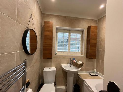 a bathroom with a toilet and a sink and a mirror at Cosy 3-Bedroom House 15mins to Olympic Village in Romford