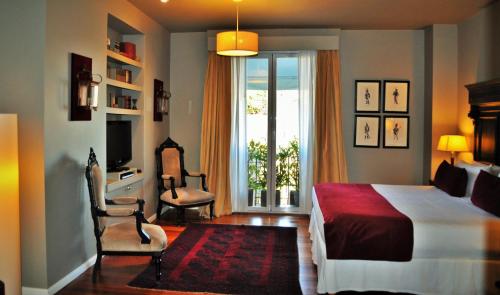 a bedroom with a bed and two chairs and a window at Legado Mitico Buenos Aires in Buenos Aires