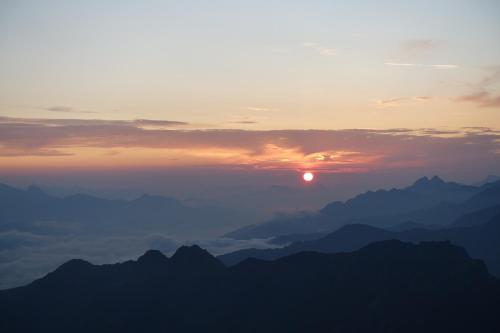 a sunset over mountains with the sun in the sky at Rasterhof in Sillian